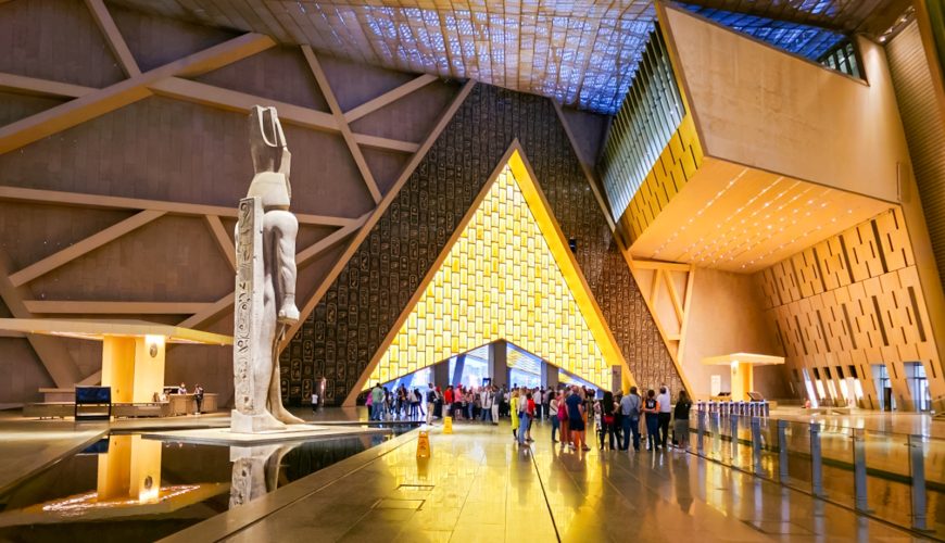 Grand Egyptian Museum exterior with pyramids in the background, showcasing ancient Egyptian artifacts
