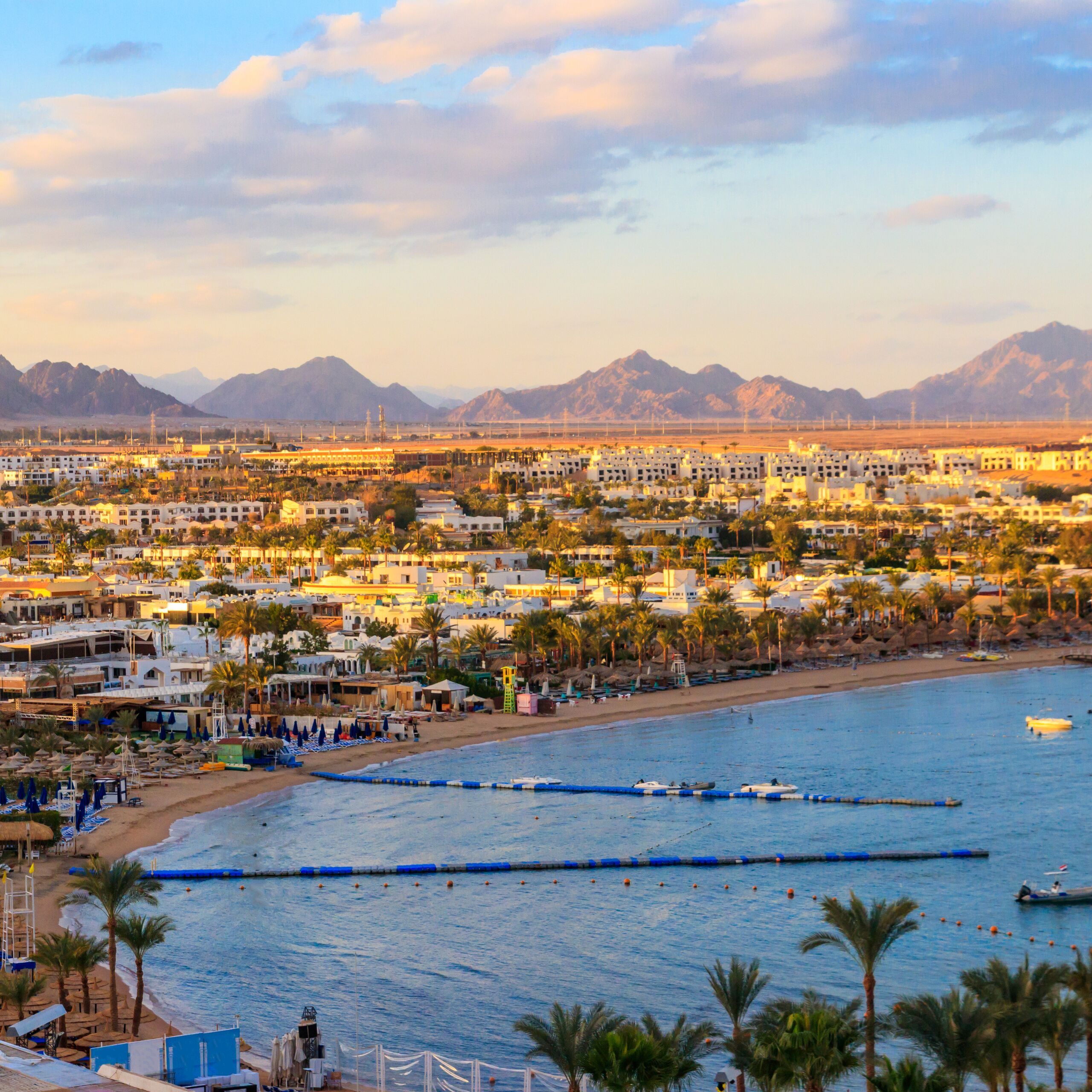 Naama Bay beach in Sharm El Sheikh with turquoise Red Sea water, golden sand, and seaside resorts