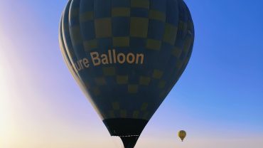 Heißluftballons steigen bei Sonnenaufgang über die historische Landschaft von Luxor am Westufer des Nils auf.