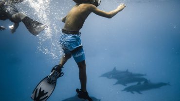 A beginner scuba diver practicing underwater breathing with scuba equipment under the supervision of a diving instructor.