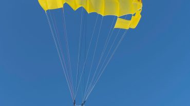 A tourist parasailing above the turquoise waters of the Red Sea during a round-trip adventure in Hurghada.